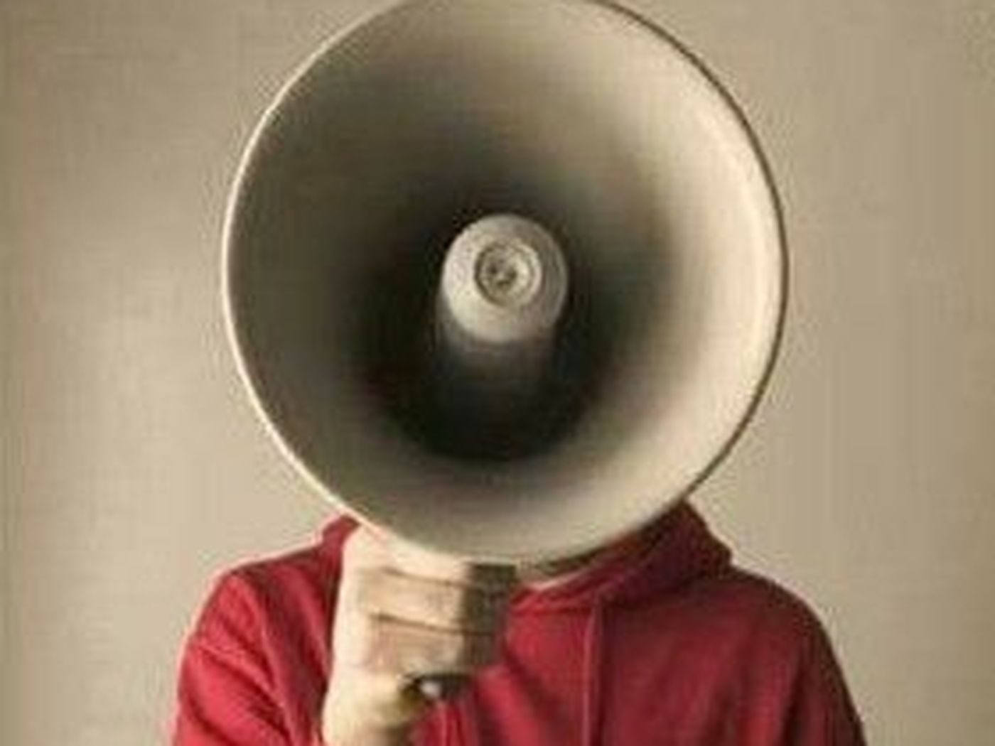 Pessoa de moletom vermelho com o rosto totalmente coberto por um megafone antigo.